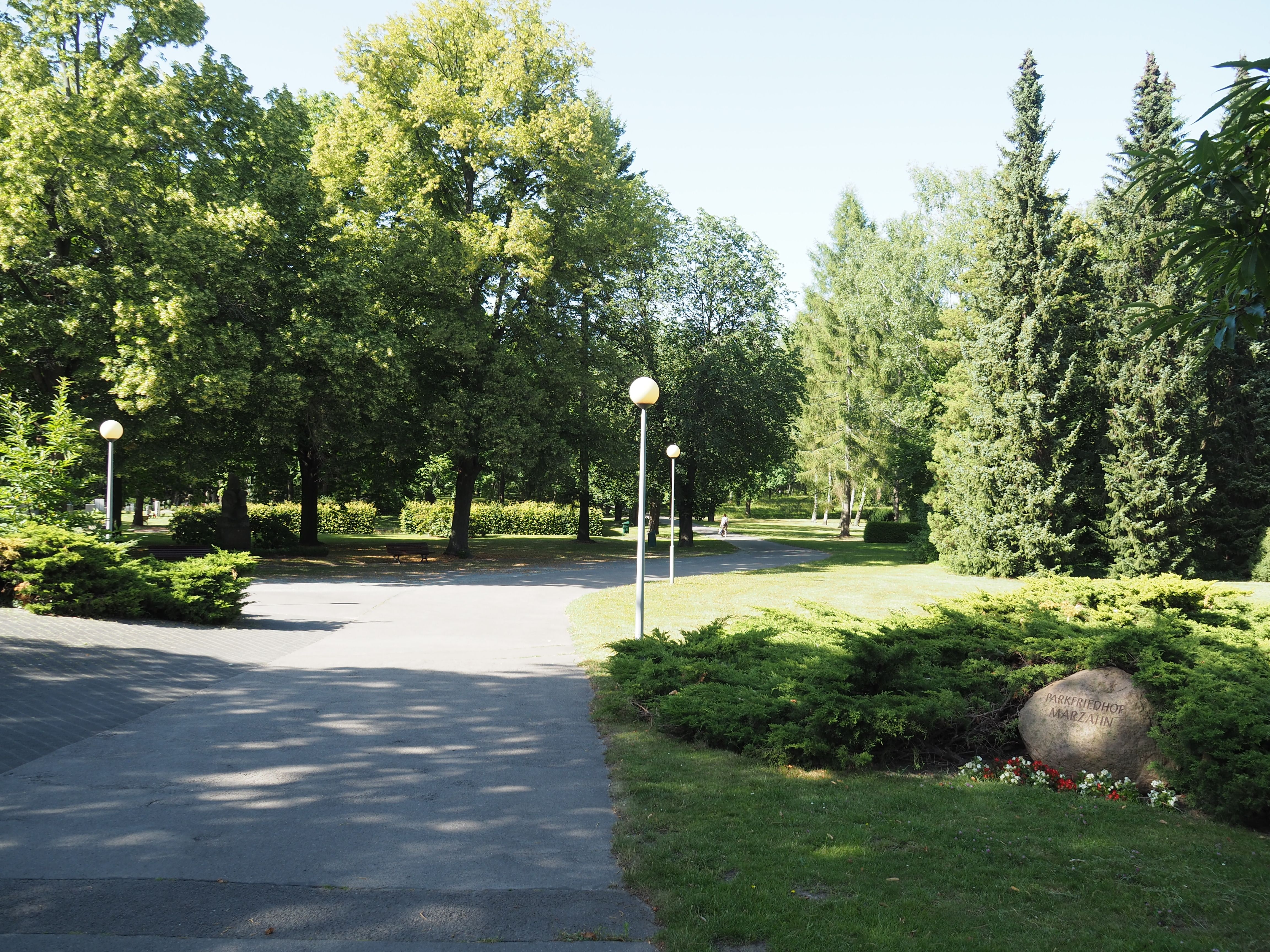 Begrünte Wege im Parkfriedhof Marzahn mit dem Namensstein des Friedhofs